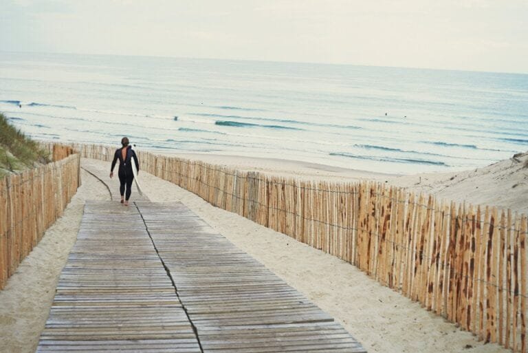 Surfer with surfboard walking to beach, Lacanau, France